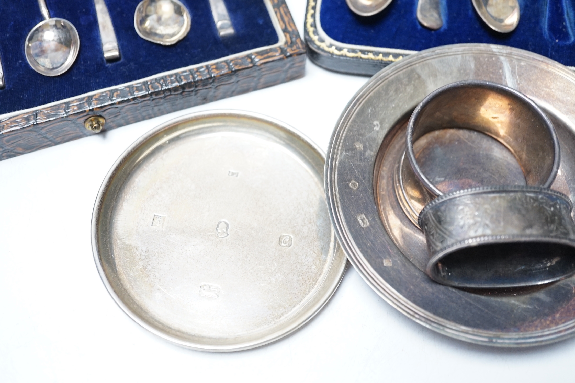 Four various silver serviette rings and a plated napkin ring, two small silver dishes, three various boxed sets of silver flatware and one part set of silver flatware.